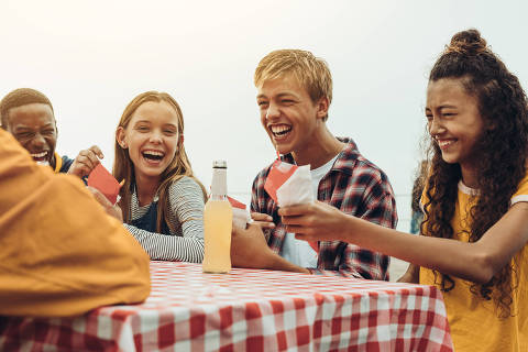 Teenage boys and girls hanging out at a restaurant. Friends talking and enjoying food and drinks at a restaurant. Foto: Jacob Lund/Adobe Stock ORG XMIT: pwnu4k DIREITOS RESERVADOS. NÃO PUBLICAR SEM AUTORIZAÇÃO DO DETENTOR DOS DIREITOS AUTORAIS E DE IMAGEM