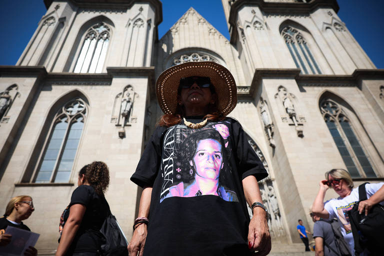 Mulher de camiseta preta estampada, chapéu e óculos escuro