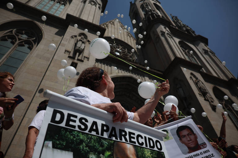 Pessoas soltam balões em frente da Catedral da Sé, enquanto seguram cartazes de desaparecidos