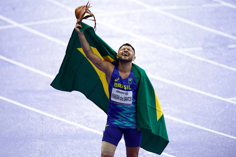 Atleta é retratado segurando uma bandeira do Brasil e um dos braços erguidos, segurando um chapéu de couro, típico do nordeste do Brasil, durante comemoração.