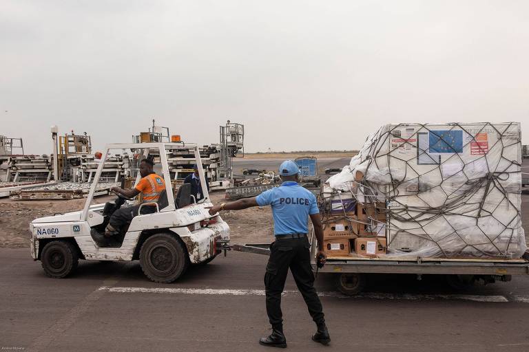 Policial gesticula para o motorista de um veículo que carrega um lote de vacinas contra mpox na pista do Aeroporto Internacional de Kinshasa, no distrito de Nsele, em Kinshasa, na República Democrática do Congo