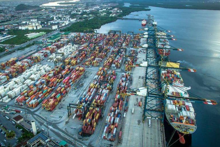 Porto de Santos visto do alto, com pilas de contêineres e navio sendo carregado