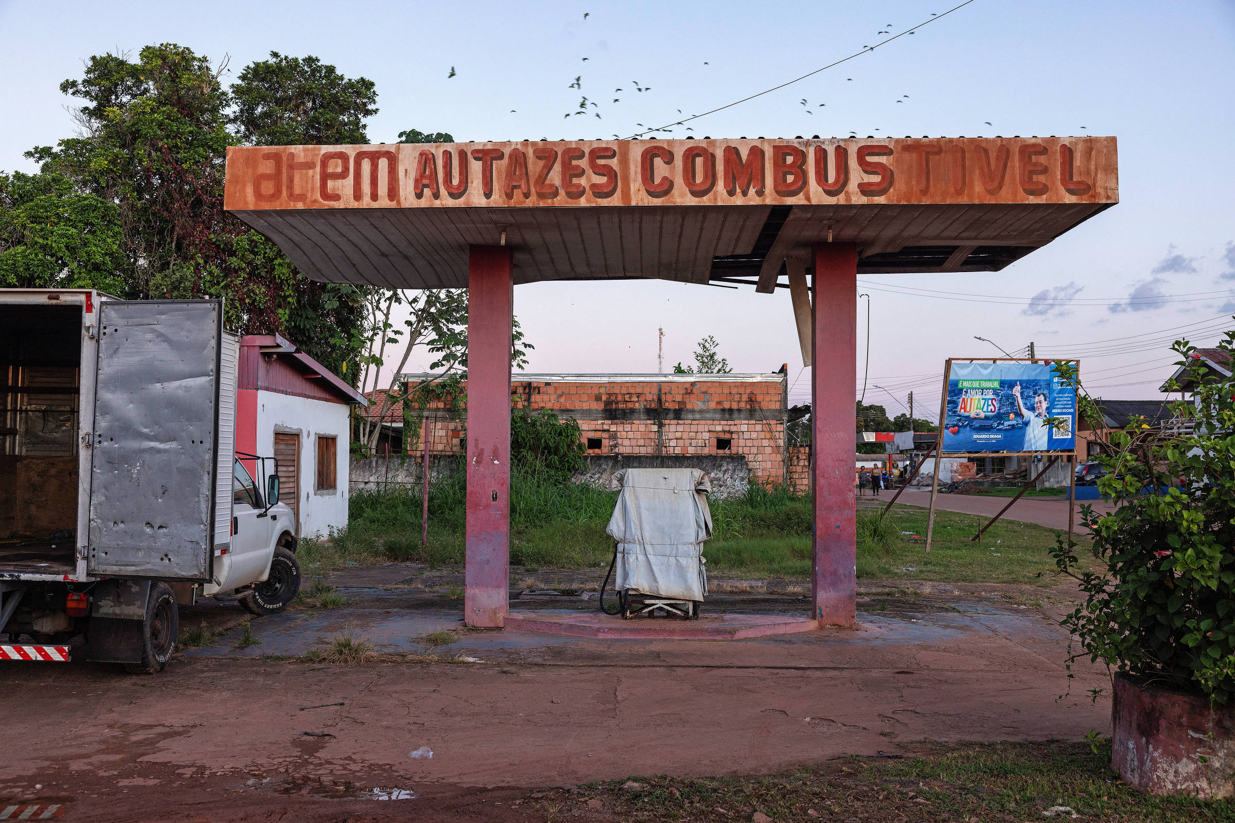 Posto de gasolina de aparência precária, com o letreiro desgastado Atem Autazes Combustível pintado no alto do teto