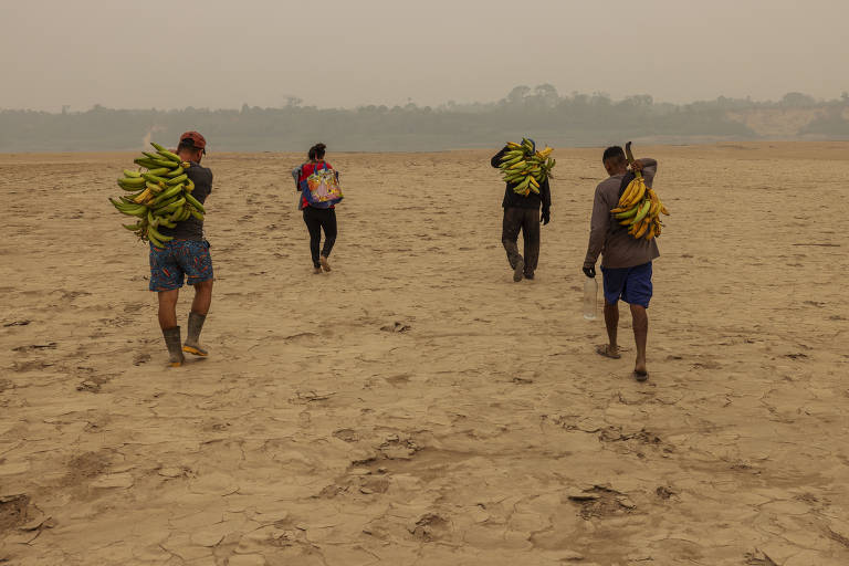 A imagem mostra cinco pessoas caminhando em um terreno seco e árido, carregando feixes de bananas nas costas. O ambiente é desértico, com uma atmosfera de fumaça ou neblina ao fundo, sugerindo condições climáticas adversas. As pessoas estão vestidas de maneira casual, e o solo é de cor clara e irregular.