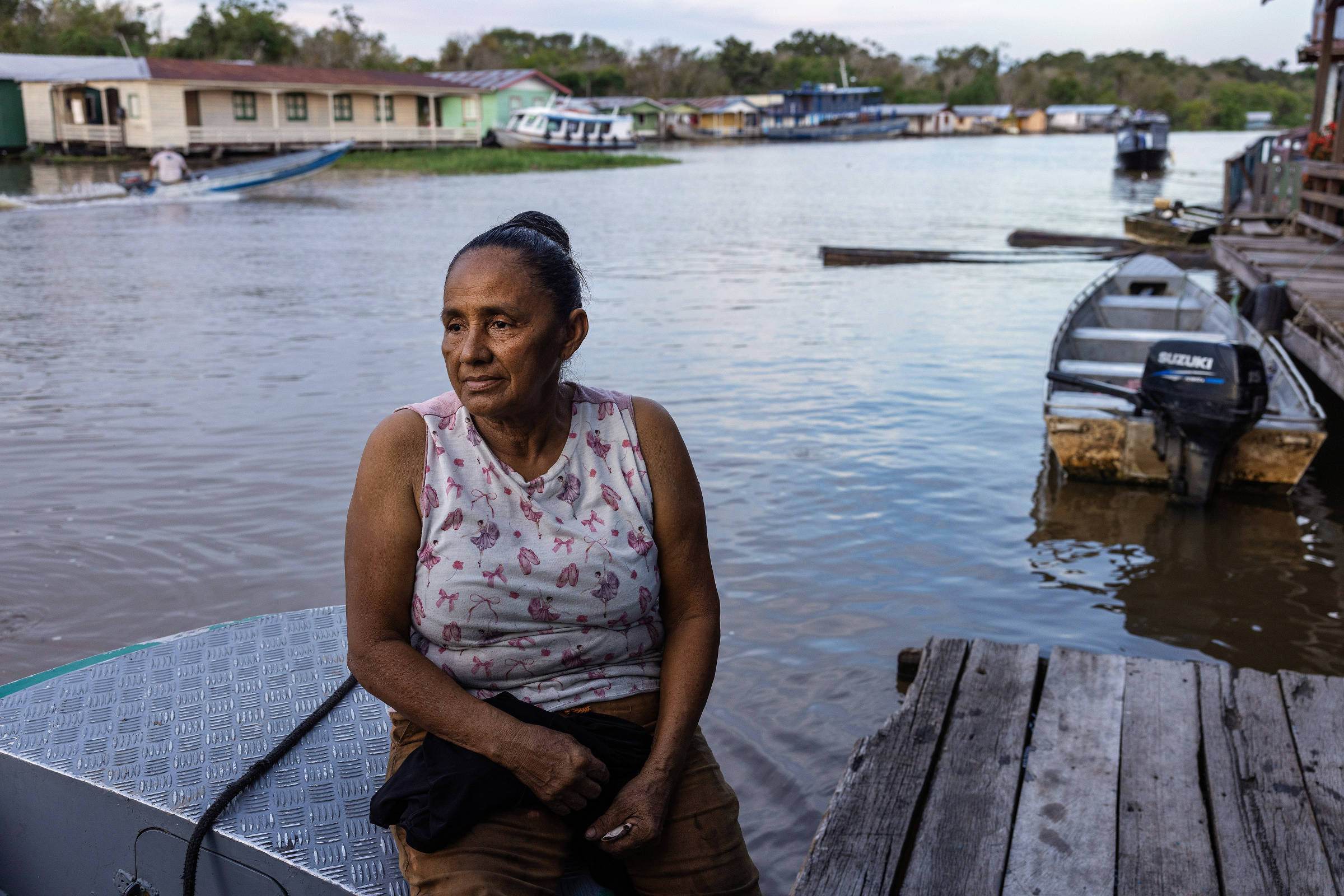 Retrato de mulher sentada em barco à beira de um rio