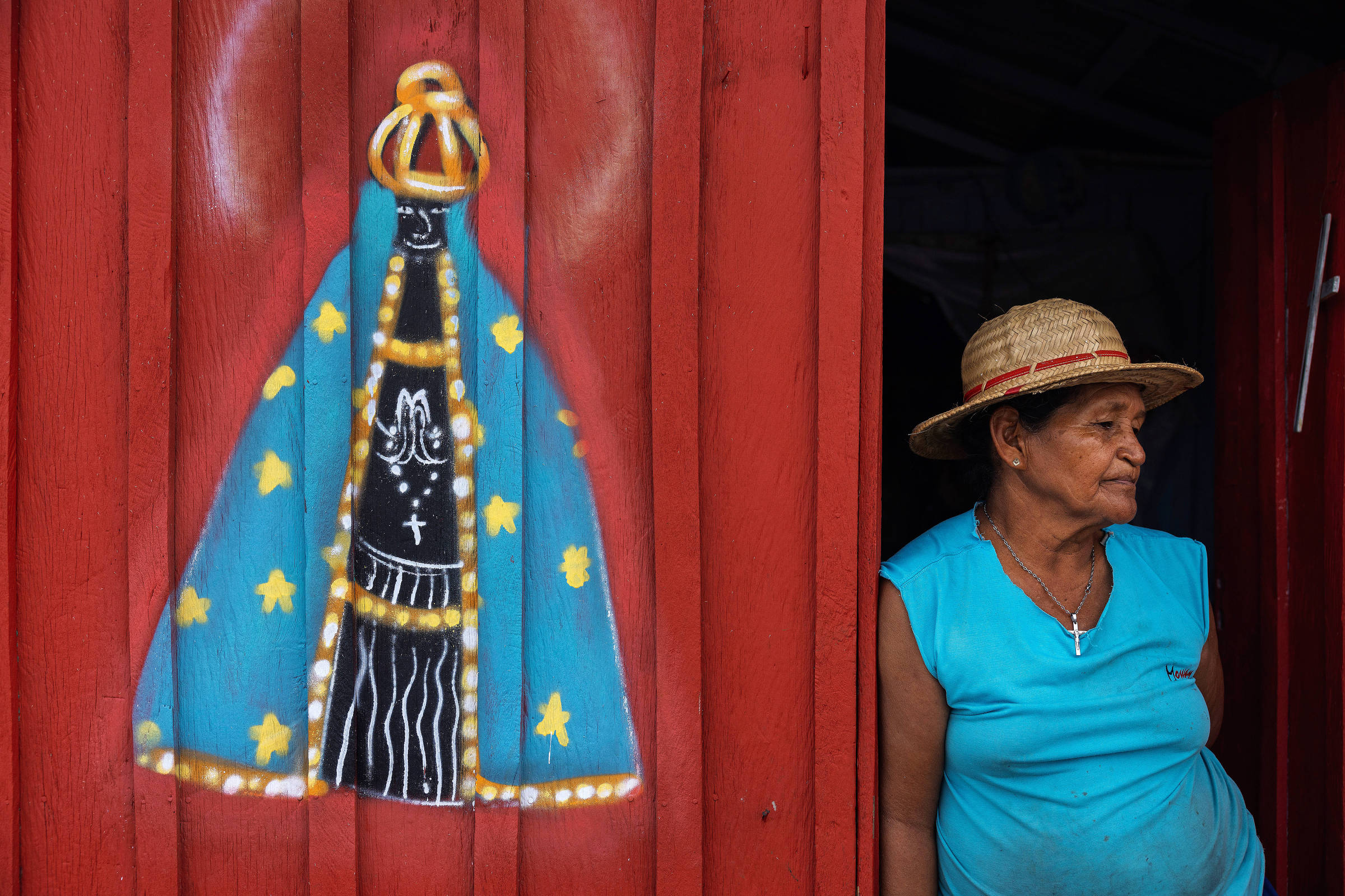 Retrato de mulher ao lado de parede de casa com Nossa Senhora Aparecida pintada