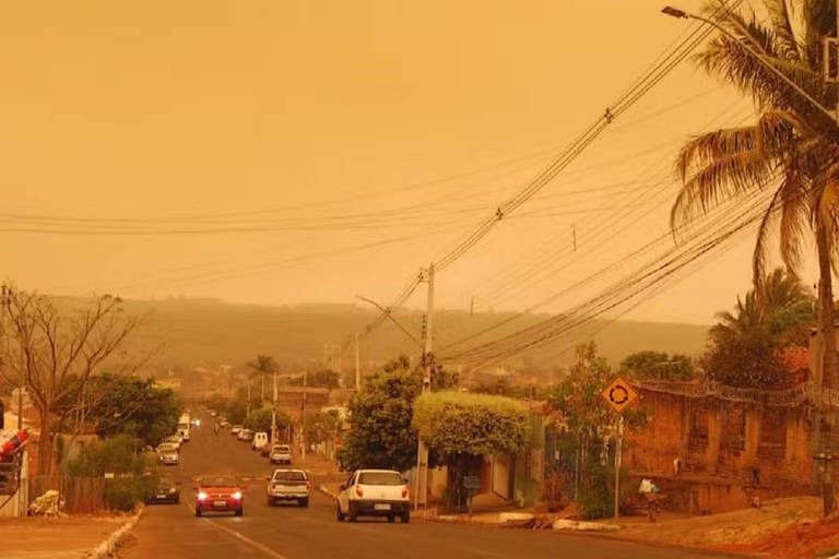 Na foto, o céu alaranjado deixa carros, árvores e casas no mesmo tom de cor