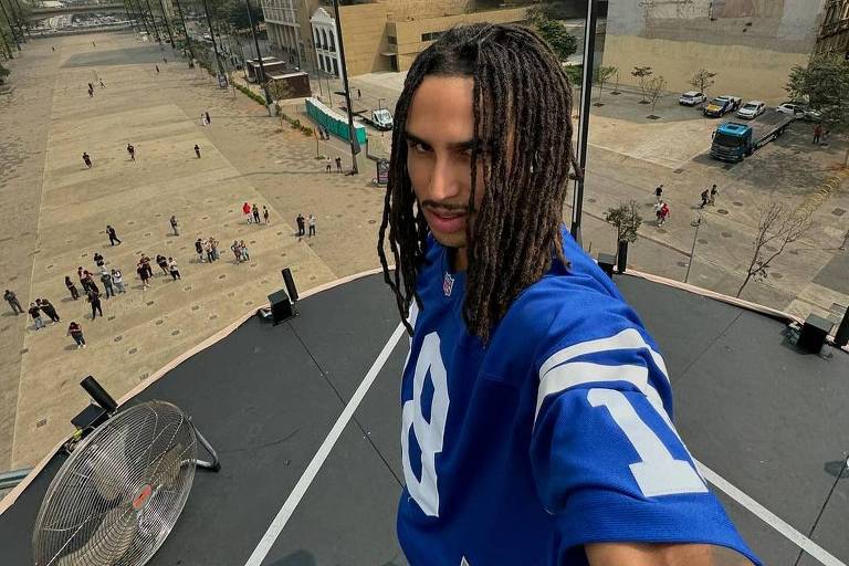 Homem de dreadlocks e camiseta azul faz selfie