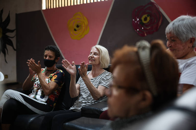 Kiki, 75 (ao centro, de cabelos grisalhos), bate palmas durante a roda de terapia comunitária integrativa em centro de convivência na zona norte de SP