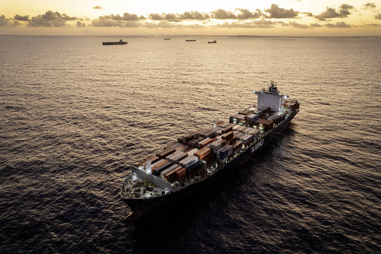 Com o sol amanhecendo e carregado de contêineres, o navio Fernão de Magalhães aguarda na costa de Pernambuco para atracar no Porto de Suape.