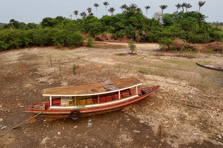 Na foto, um barco está sobre uma faixa de areia seca, onde deveria estar um rio