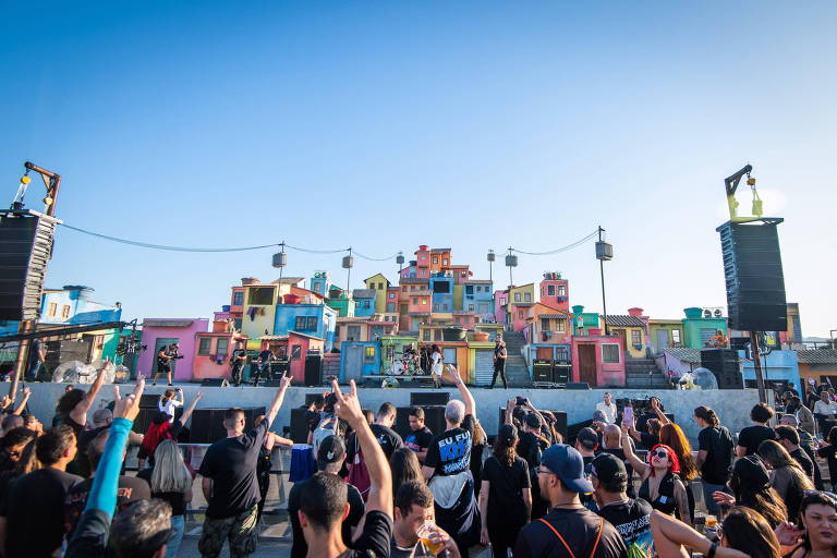 Foto mostra o palco Espaço Favela, na edição do Rock In Rio de 2022. Pessoas estão em frente ao palco com as mãos levantadas, dançando. 