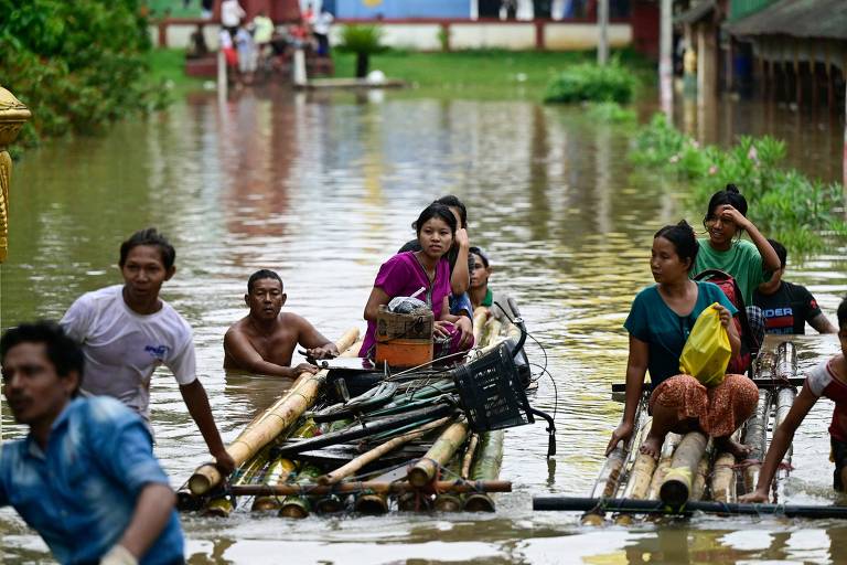 Pessoas usam estruturas feitas com bambu para se locomover em área alagada emToungoo

