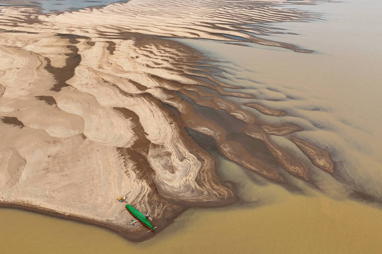 imagem aérea mostra bancos de areia em rio durante seca, há uma canoa na extremidade do banco e, na parte inferior da imagem, a água barrenta do rio