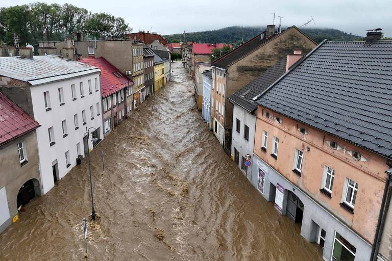 Um rio de água marrom passa entre casas históricas e coloridas