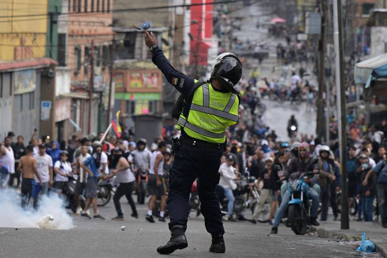 Imagem mostra policial arremessando bombas em direção a uma algomeração de pessoas, que foge