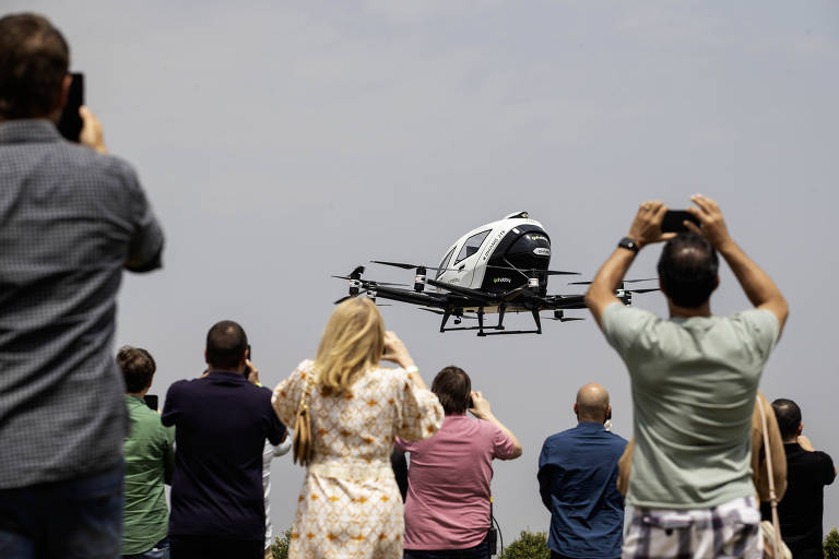 Pessoas observam aeronave decolando no céu. elas apontam as câmeras para registrar o momento.