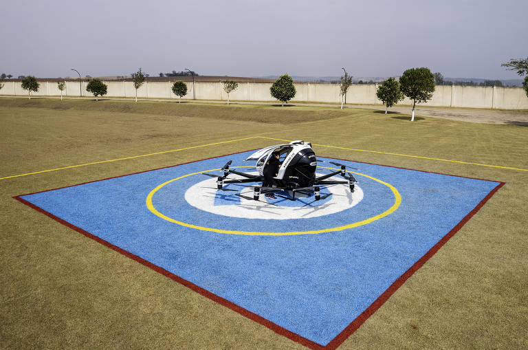 eVtol é visto parado sobre heliponto em um campo aberto.