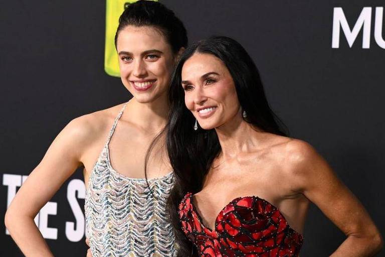 Duas mulheres brancas posam em trajes de gala, sorrindo.