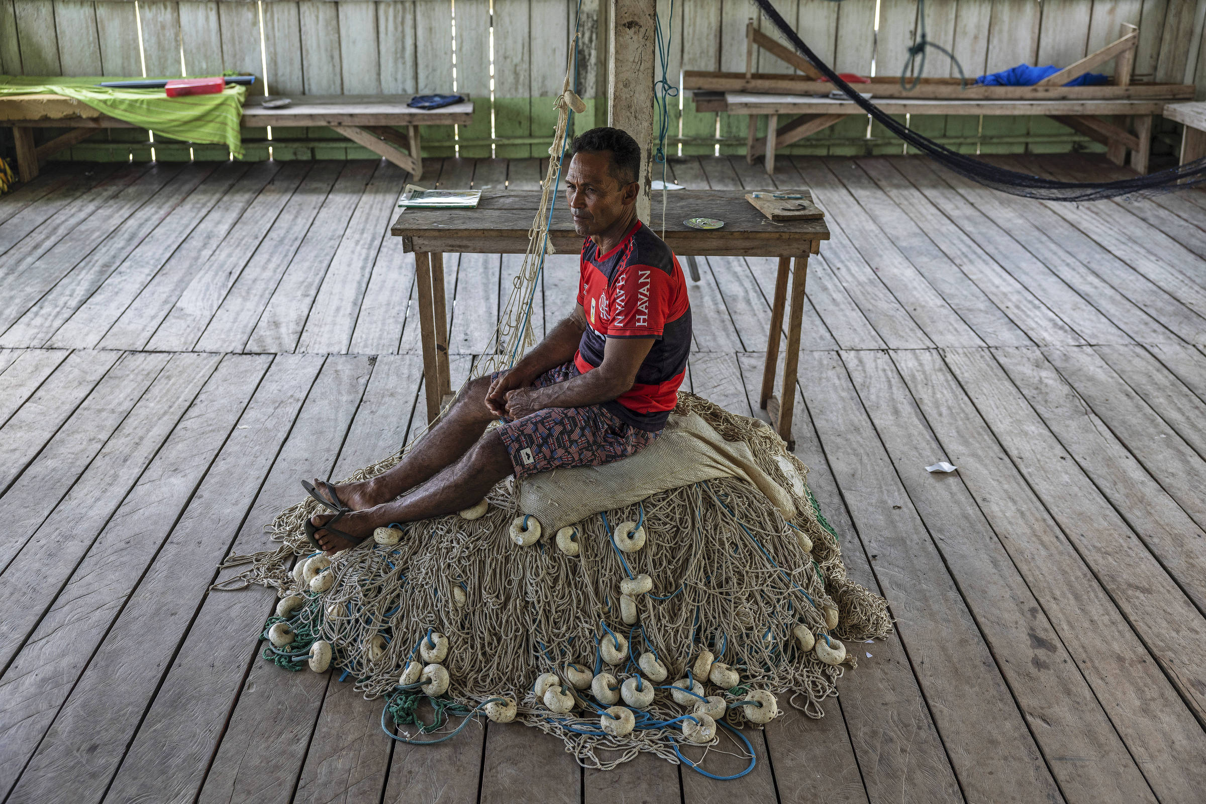 Pescador sentado em cima de redes de pesca