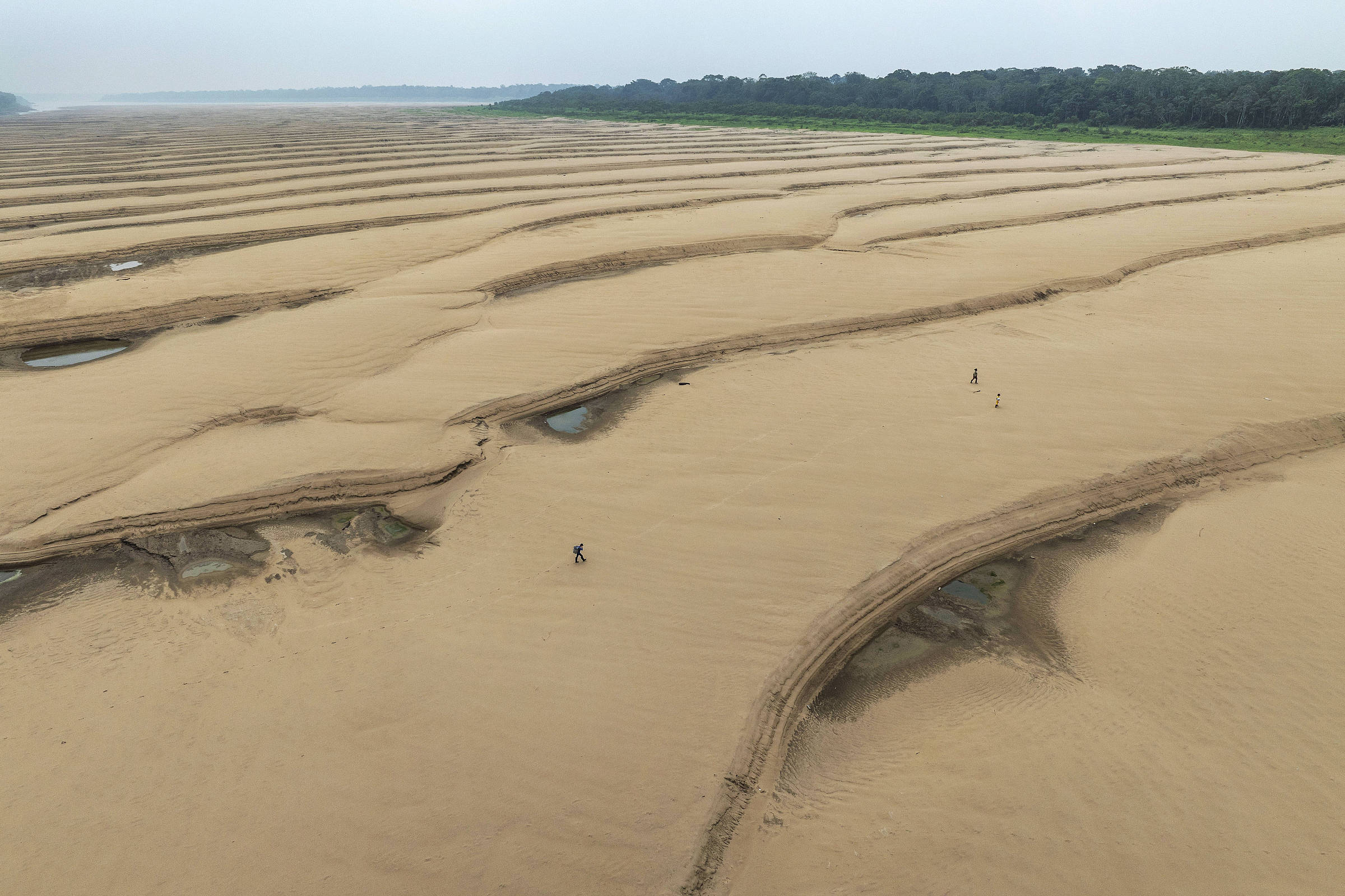 Ribeirinhos atravessam bancos de areia de rio