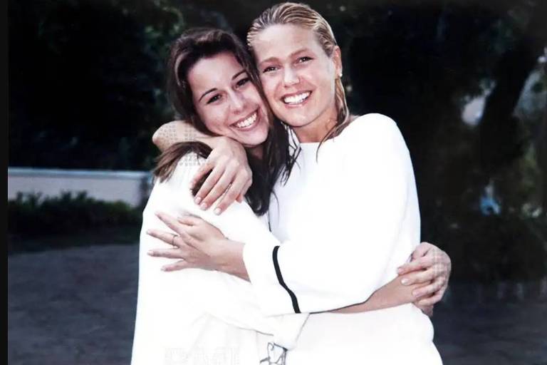 Em foto colorida, duas mulheres sorriem abraçadas