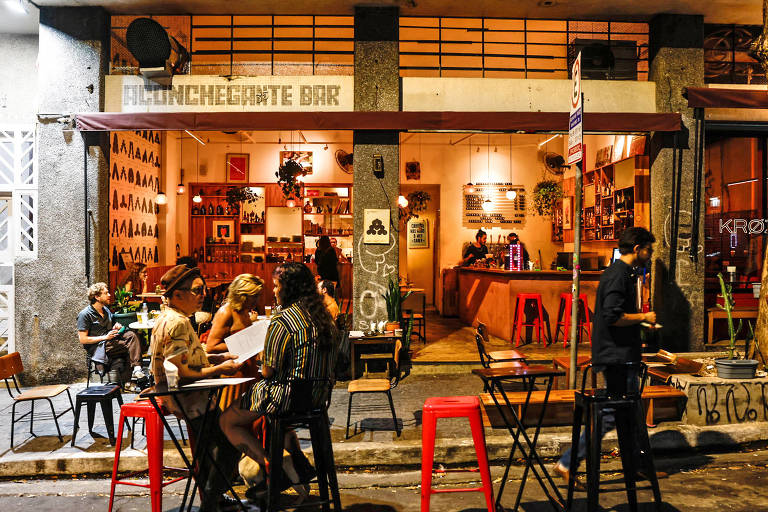 Clientes ocupam mesas na calçada do Aconchegante Bar