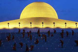 Buddhist monks light candles during Vesak Day, an annual celebration of Buddha's birth, enlightenment and death, at Wat Dhammakaya in Pathum Thani province