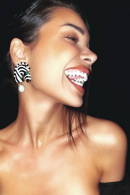 A imagem mostra uma mulher sorrindo amplamente, destacando seus dentes brancos.