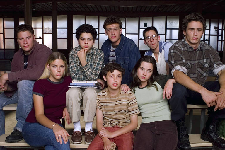 Um grupo de oito adolescentes está posando em um ambiente escolar.