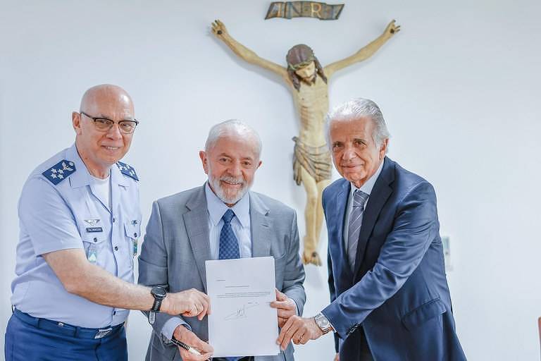 tres homens seguram um pedaço de papel com uma escultura de cristo atrás