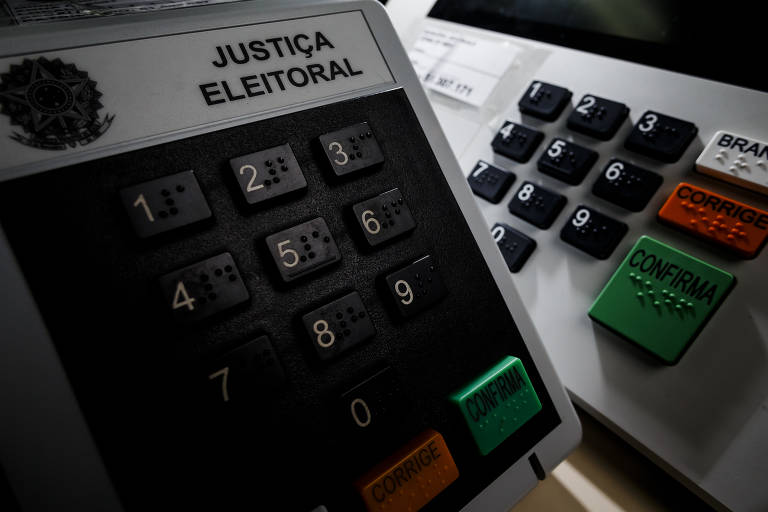 Duas urnas eletrônicas com teclado e a inscrição "Justiça Eleitoral"