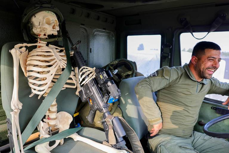 Uma foto tirada no sul de Israel, na fronteira com Gaza, mostra um soldado israelense posando para uma foto com um esqueleto de plástico encontrado durante operações militares na Faixa de Gaza