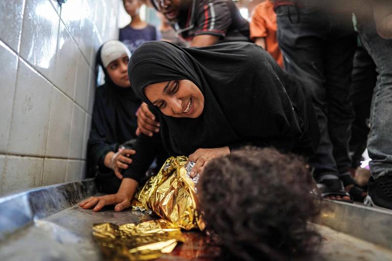 Uma mãe se despede do corpo de seu filho, morto após o bombardeio israelense durante a noite em al-Maghazi, no centro da Faixa de Gaza, no necrotério do hospital dos Mártires de Aqsa, em Deir el-Balah
