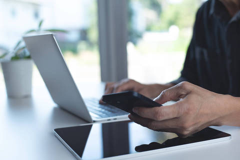 Business man working on laptop computer and using mobile phone with digital tablet on table at home office. Working at home, telecommuting, e-learning concept