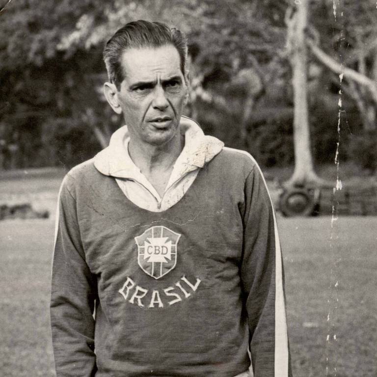 O jornalista João Saldanha, que dirigiu a seleção brasileira em 1969, veste um agasalho com a inscrição "Brasil" na parte da frente; a foto é em preto e branco