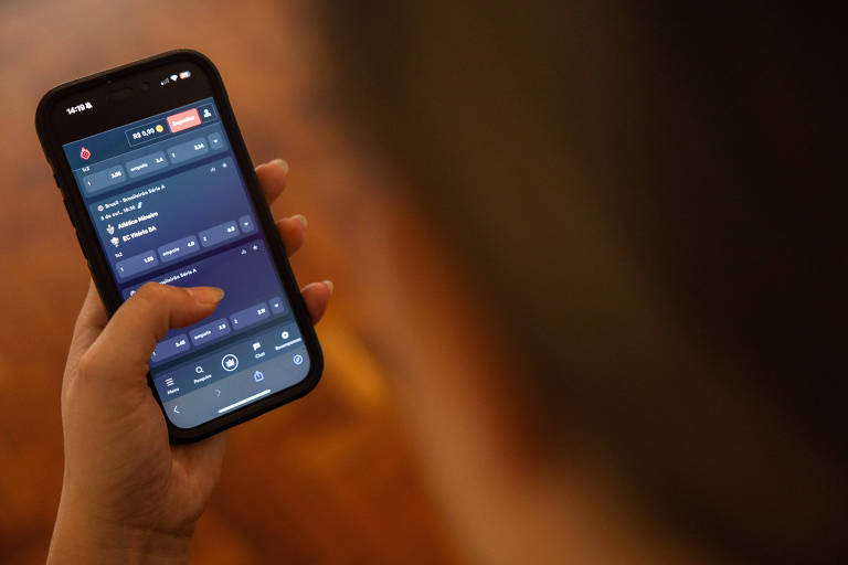 Pessoa segura celular com aplicativo de apostas