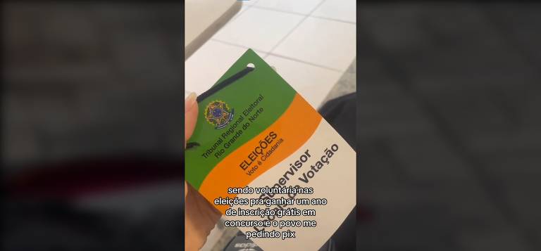 Imagem mostra uma mão de uma mulher branca segurando o crachá oficial do Tribunal Regional do rio Grande do Norte. Um texto sobrepõem o crachá com a mensagem: "sendo voluntária nas eleições para ganhar um ano de inscrição grátis em concurso e o povo me pedindo pix