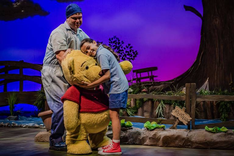 Criança abraça boneco do Ursinho Pooh em peça de teatro