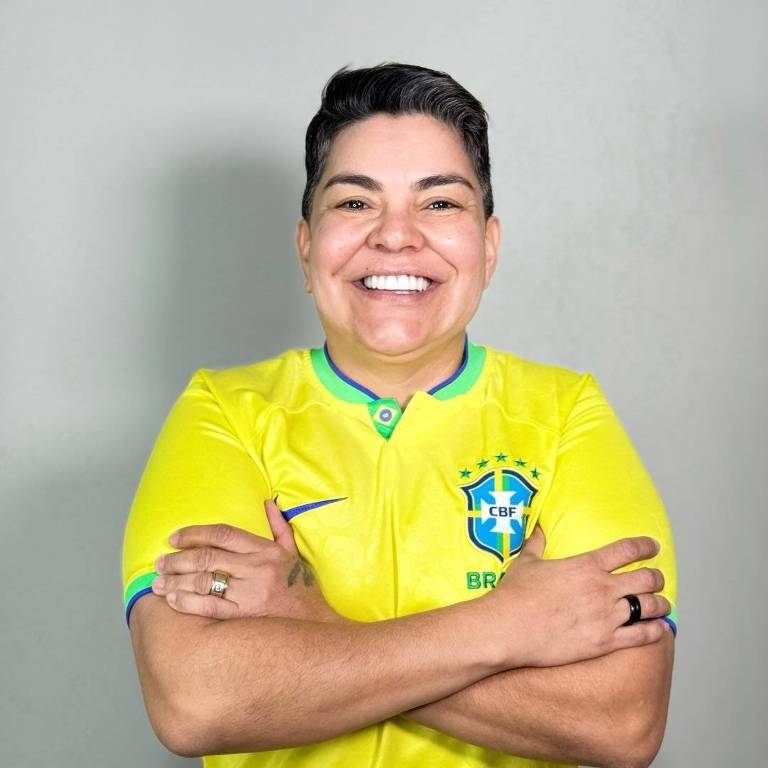 Uma pessoa está sorrindo e posando com os braços cruzados