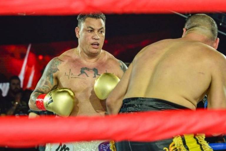 Dois homens num ringue de boxe, um deles está de costas