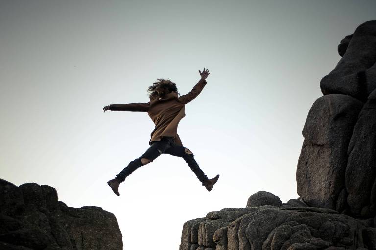 Menina jovem pulando de uma pedra para outra