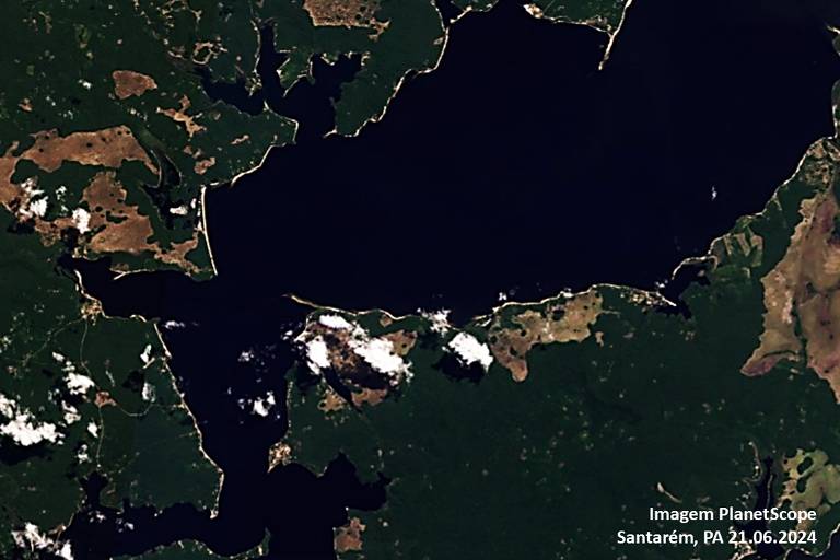 A imagem mostra uma vista aérea de uma região costeira, com uma grande área de água escura no centro, cercada por áreas de vegetação e terra. Há algumas formações de nuvens brancas visíveis sobre a água e em algumas áreas de terra.