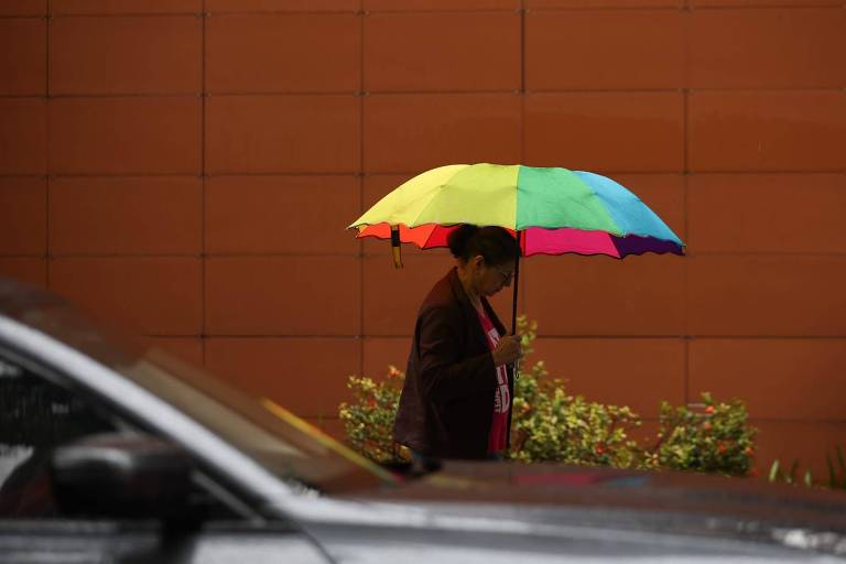 Pessoa anda em rua com guarda-chuva