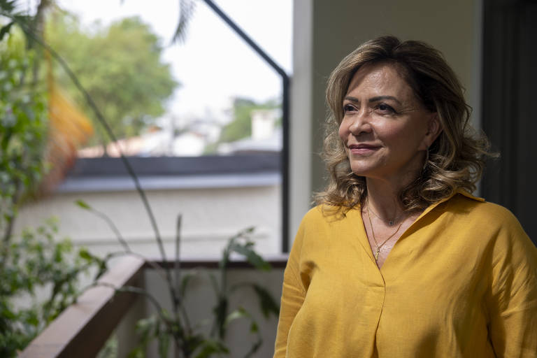 Mulher de cabelos castanhos claros/loiros é fotografada olhando para fora de uma sacada