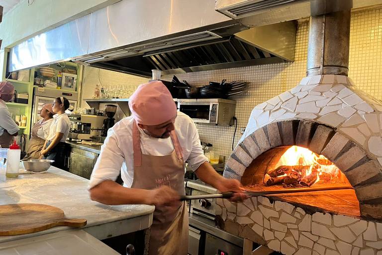 homem assa pizza em forno a lenha