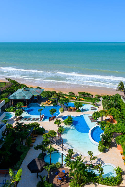 Parte externa de um hotel, com piscinas e árvores