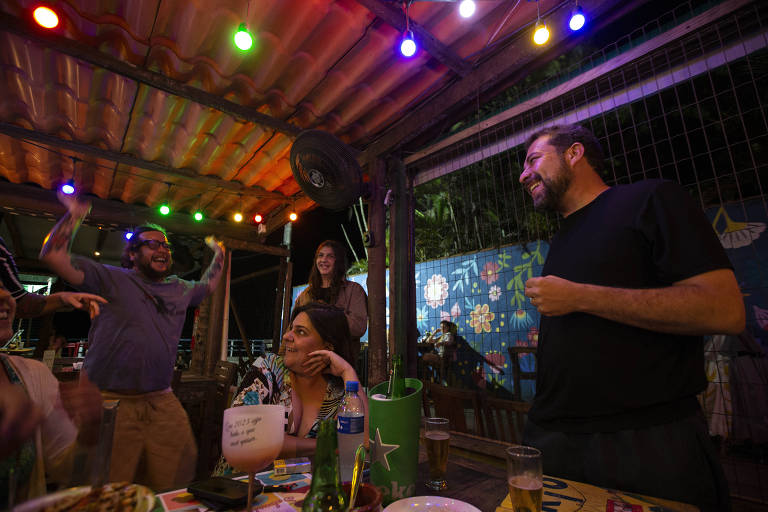O deputado federal Guilherme Boulos (PSOL), que foi candidato à Prefeitura de São Paulo, conversa com pessoas em um estabelecimento