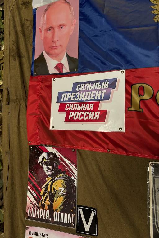 Em unidade da frente, foto de Putin com os dizeres Presidente Forte, Rússia Forte; abaixo, cartaz diz Batalhão, Fogo!