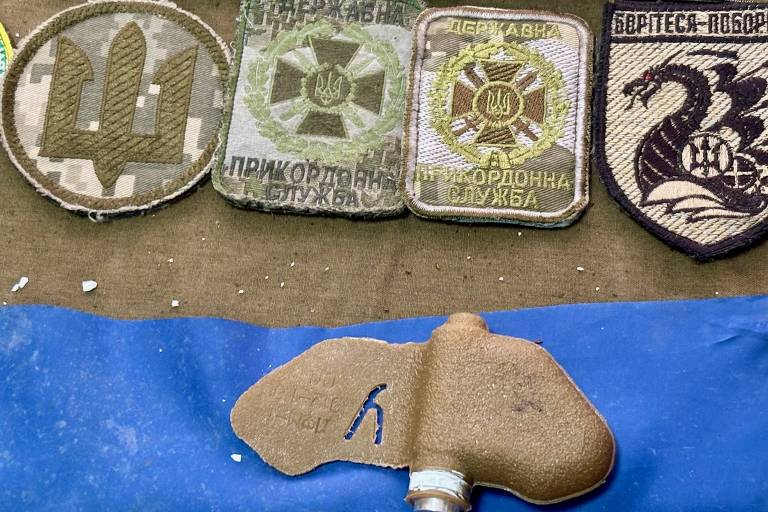 Mina antipessoal e insígnias de soldados ucranianos recolhidas pela Rússia